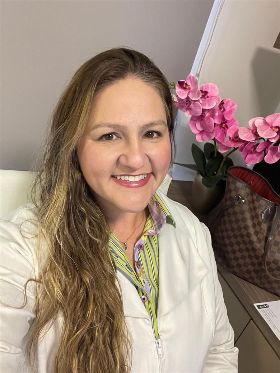 Dra. Raphaela Mannarino, cardiologista no Rio de Janeiro, sorrindo de jaleco no consultório